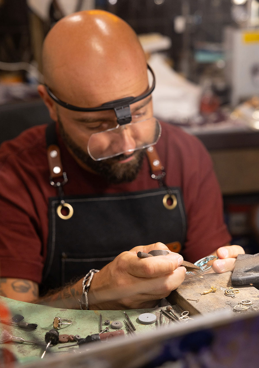 Flavio Toro al lavoro al banchetto del laboratorio orafa con la lente da testa